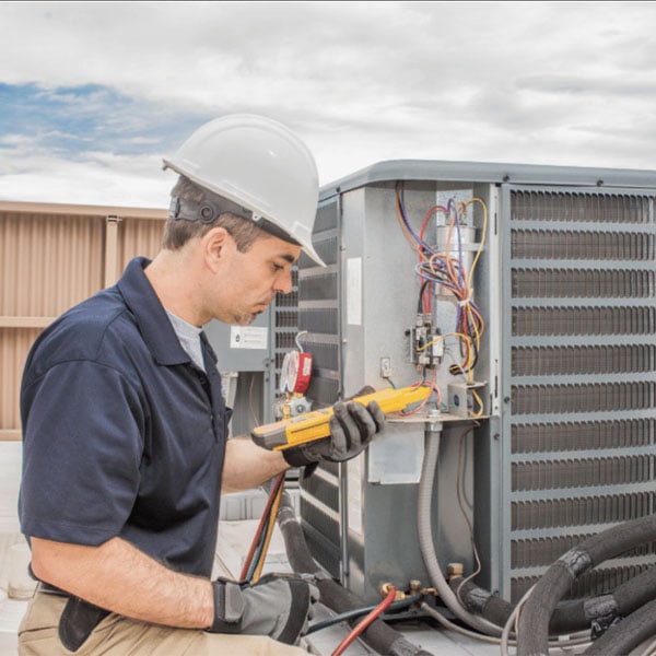 Performance Mechanical Group's technician performing maintenance on outdoor cooling unit.