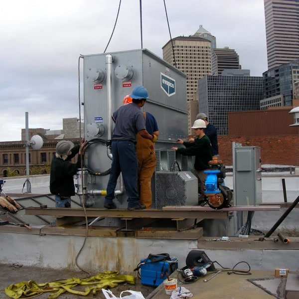 Performance Mechanical Group's technician's installing a rooftop cooling unit.