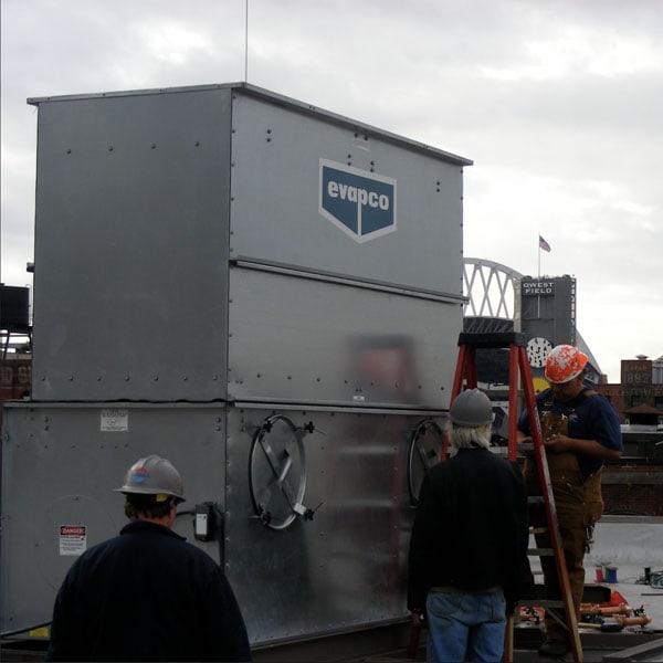 Performance Mechanical Group’s technicians installing a large HVAC unit on a city rooftop.