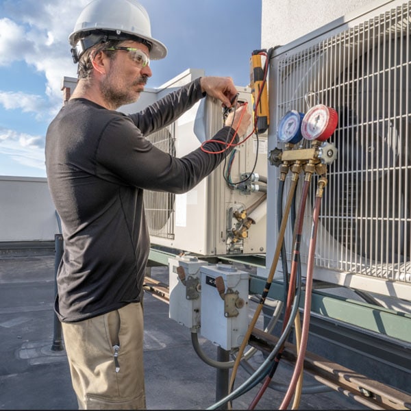 Performance Mechanical Group technician using gauges and hoses to check the system's pressure.