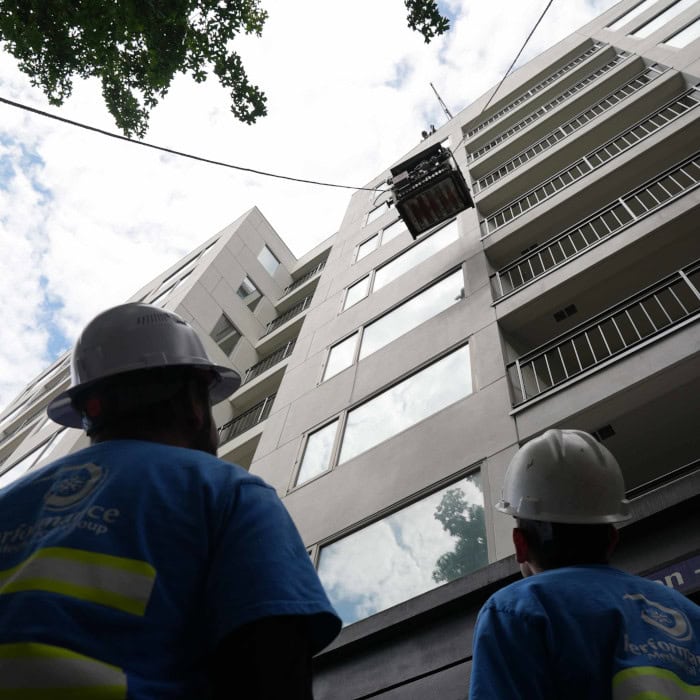 Performance Mechanical Group’s technicians standing on top of building with material in the background.