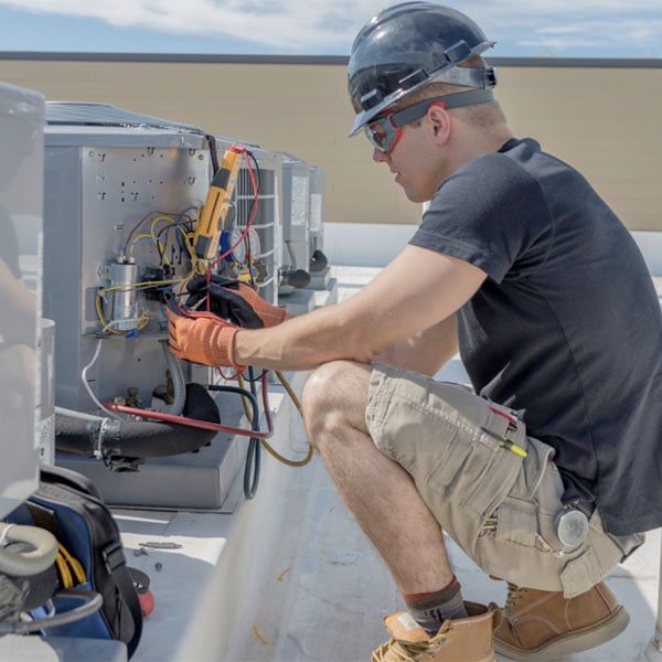 Performance Mechanical Group technician working on an HVAC unit on a building rooftop.